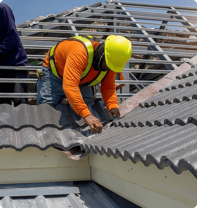 Worker installing grey concrete tiles over a metal roof frame | Blue Rock Roofing & Construction
